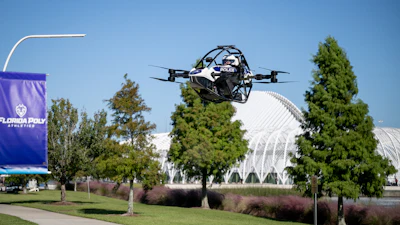 Police drone in flight over Florida Poly campus with trees and modern architecture in background