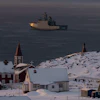 Arctic coastal settlement with red church, snow-covered buildings, and icebreaker ship in Greenlandic waters