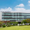 Hyundai Transys modern corporate headquarters building with glass facade and landscaped grounds under blue sky