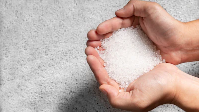 Hands holding white salt or sugar crystals against concrete background