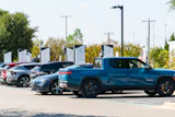 Row of electric vehicles charging at outdoor station with multiple chargers