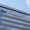 Modern glass and steel office building with company signage on facade under blue sky