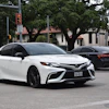 White Toyota Camry sedan parked on urban street with trees and buildings in background
