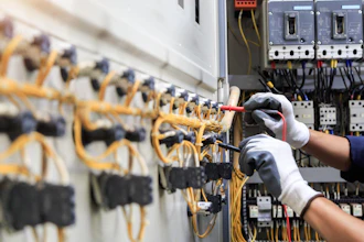 Electrician installing yellow wiring in industrial circuit breaker panel with safety gloves