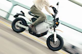 Person riding white and black electric scooter on road with yellow lane marking