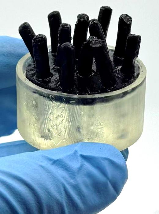 Black rod-like structures in clear cylindrical container against blue background