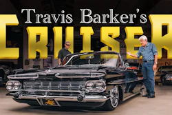 Travis Barker's classic black convertible cruiser displayed in showroom with two men standing beside the vintage 1950s car