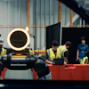 Boston Dynamics robot Spot with glowing head ring displayed at industrial facility with workers in safety vests observing