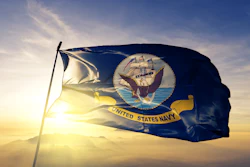 United States Navy flag waving against golden sunset sky with mountains in background