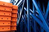 Orange and blue industrial warehouse racking system with metal shelving and structural beams