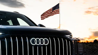 Black Audi vehicle with American flag at sunset