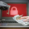 Ransomware extortion concept: hands exchanging money and key with padlock symbol on laptop screen