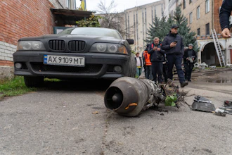 Damaged BMW sedan with detached engine component displayed on ground during investigation with officials and onlookers in urban courtyard