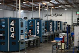 Industrial manufacturing facility with blue CNC machines and Sena CutSend signage on warehouse wall