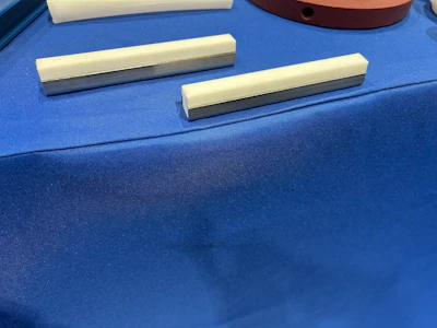 Two cream and metallic gray rectangular drawer handles displayed on blue fabric surface