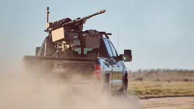 Military-equipped GMC pickup truck driving through dusty desert terrain