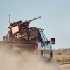 Military-equipped GMC pickup truck driving through dusty desert terrain