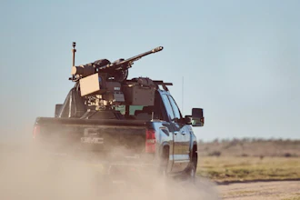 Military-equipped GMC pickup truck driving through dusty desert terrain